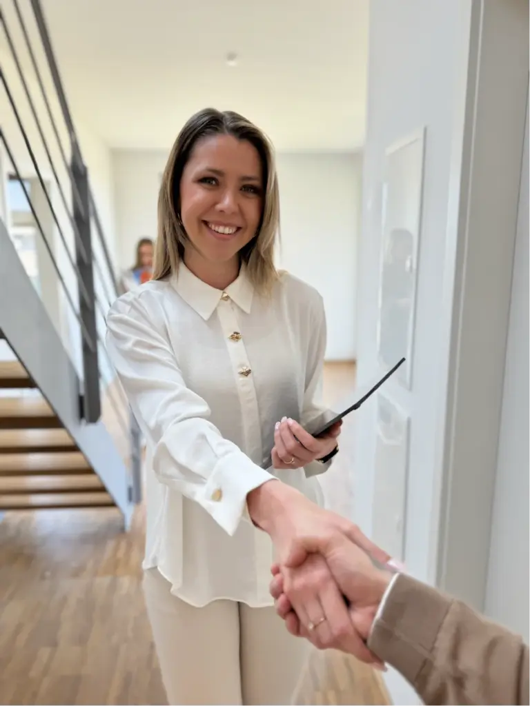 Begrüßung eines Kunden durch eine Mitarbeiterin von Wohlfeil Immobilien bei einer Besichtigung