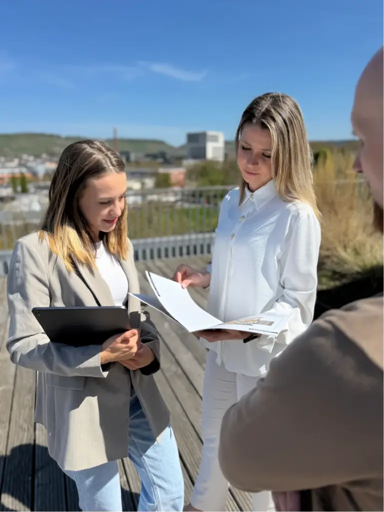Mitarbeiterinnen von Wohlfeil Immobilien prüfen ein gedrucktes Exposé